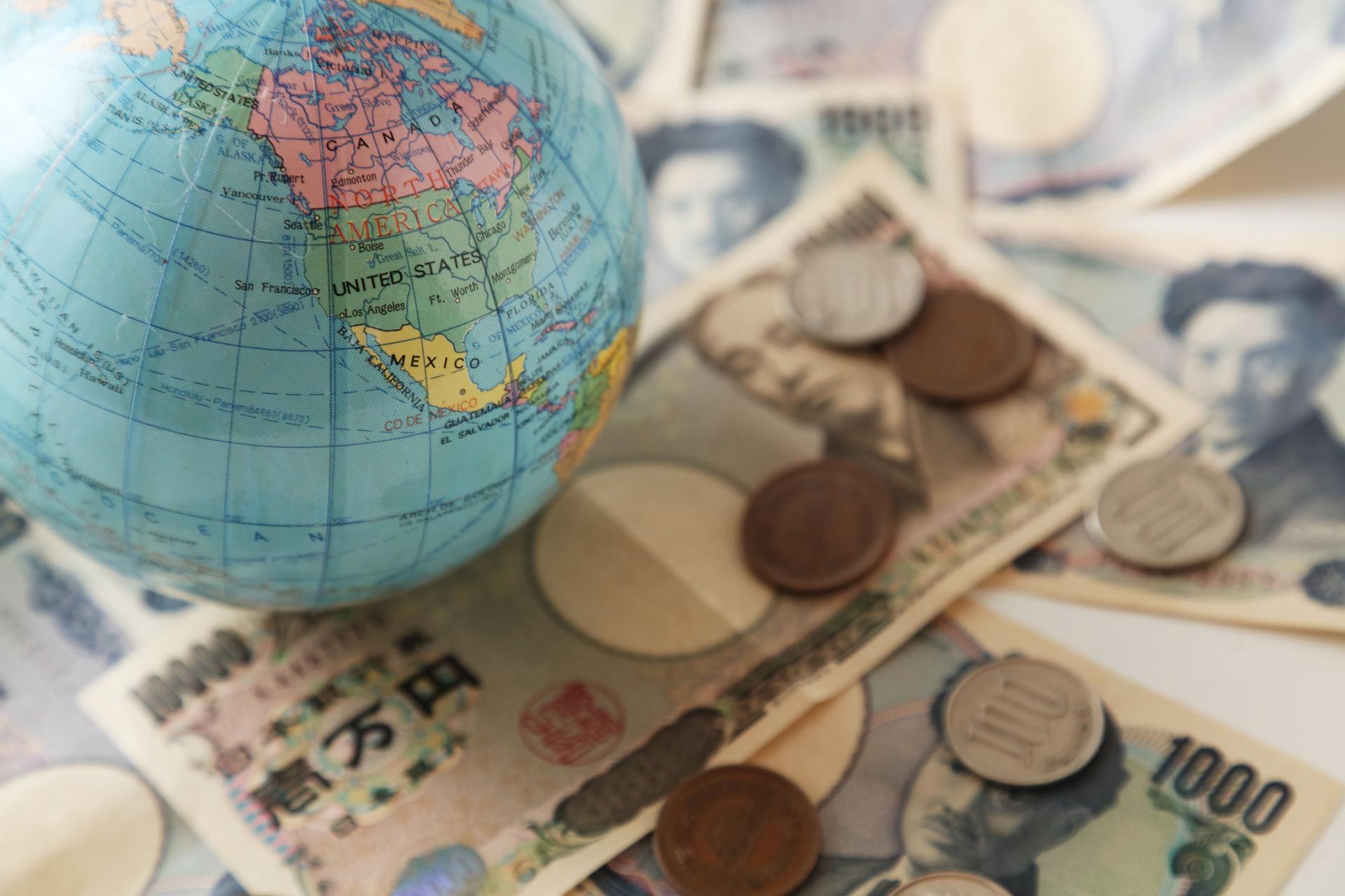 Petit globe terrestre sur la surface couverte avec les multiples factures de billet de banque, faible profondeur de composition de champ